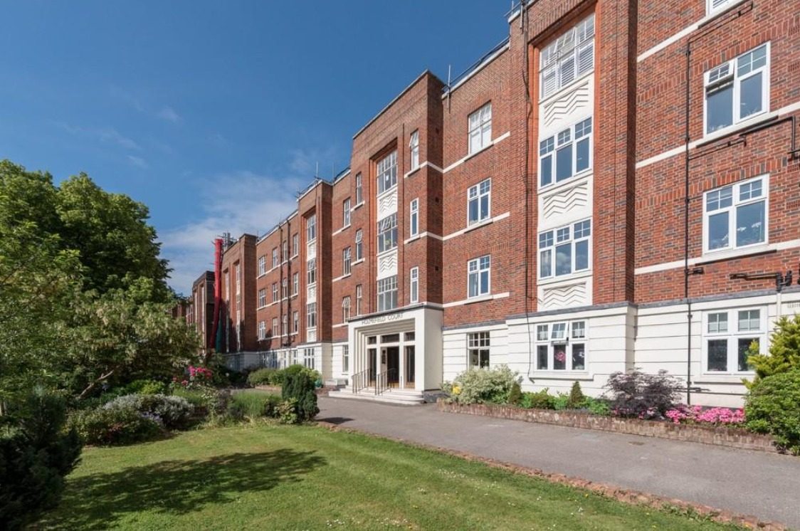 Homefield Court, Belsize Park – four-storey red-brick mansion block with white stone detailing, photographed head-on from the front entrance with landscaped gardens in the foreground.