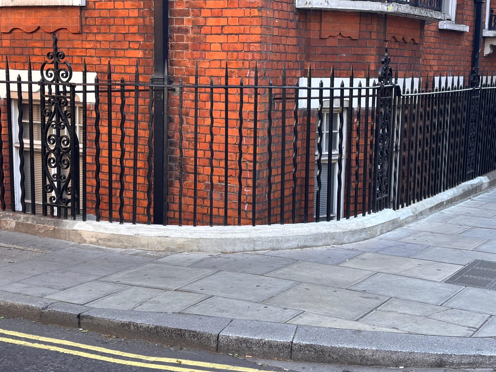 Restored period cast-iron railings on a North London block &mdash; curved corner section, repainted with rust treatment and made-good base by CJD
