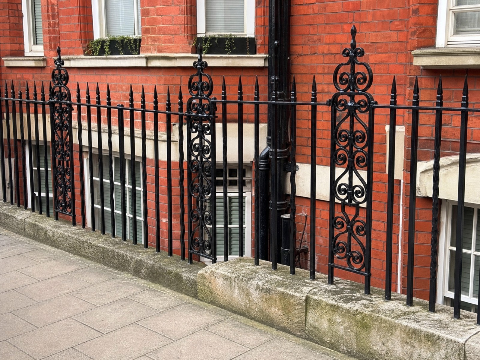 Restored black cast-iron railings outside a red-brick London residential block.